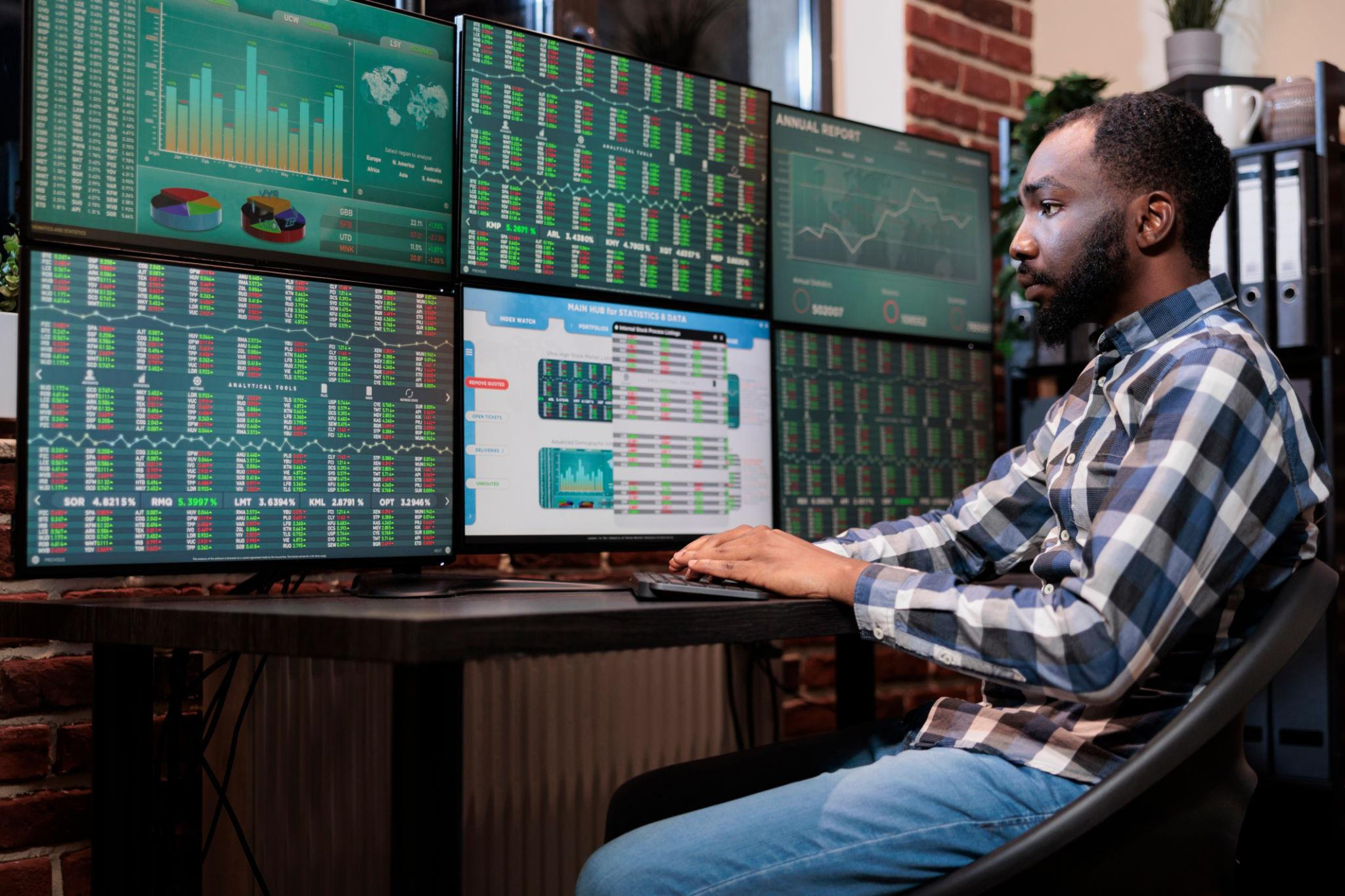 Brokerage company employee sitting at multi monitor workstation while trading risk free assets. in forex jireenya jijjiiruu